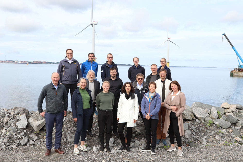 Group picture with floating wind turbines in the background.