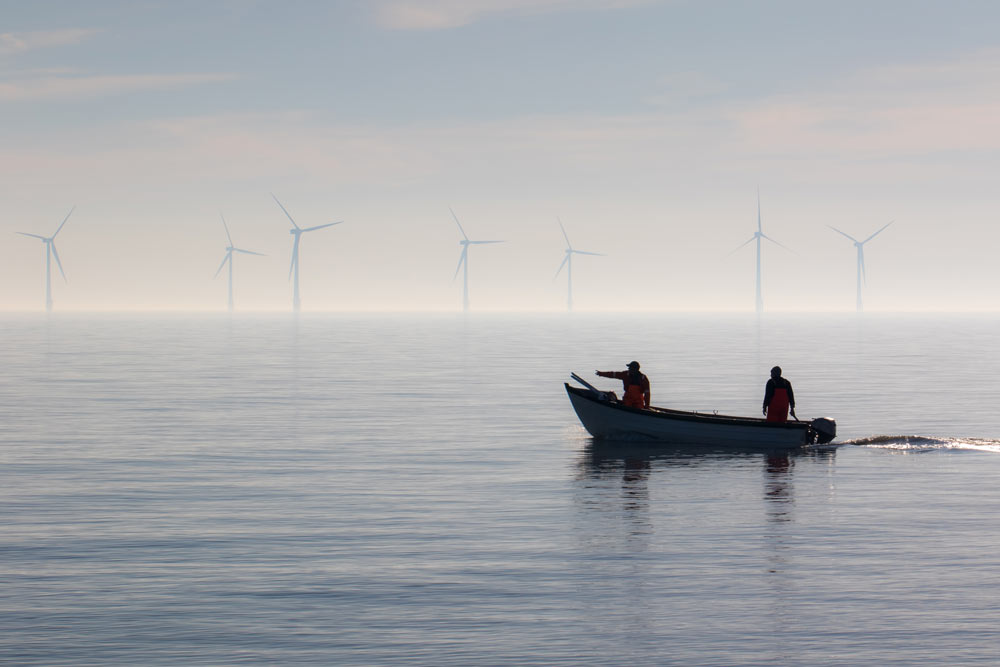 Small boat with offshore wind turbines in the background.