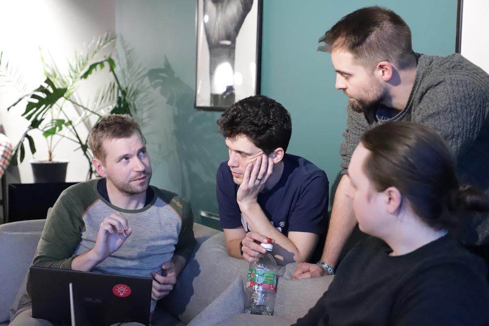 Programmers holding a meeting around a laptop, on a sofa.