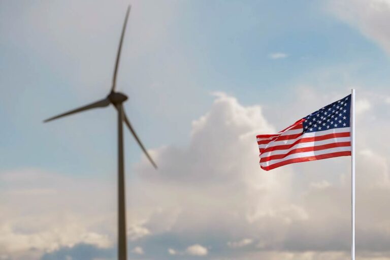 US flag with wind turbine in the background.